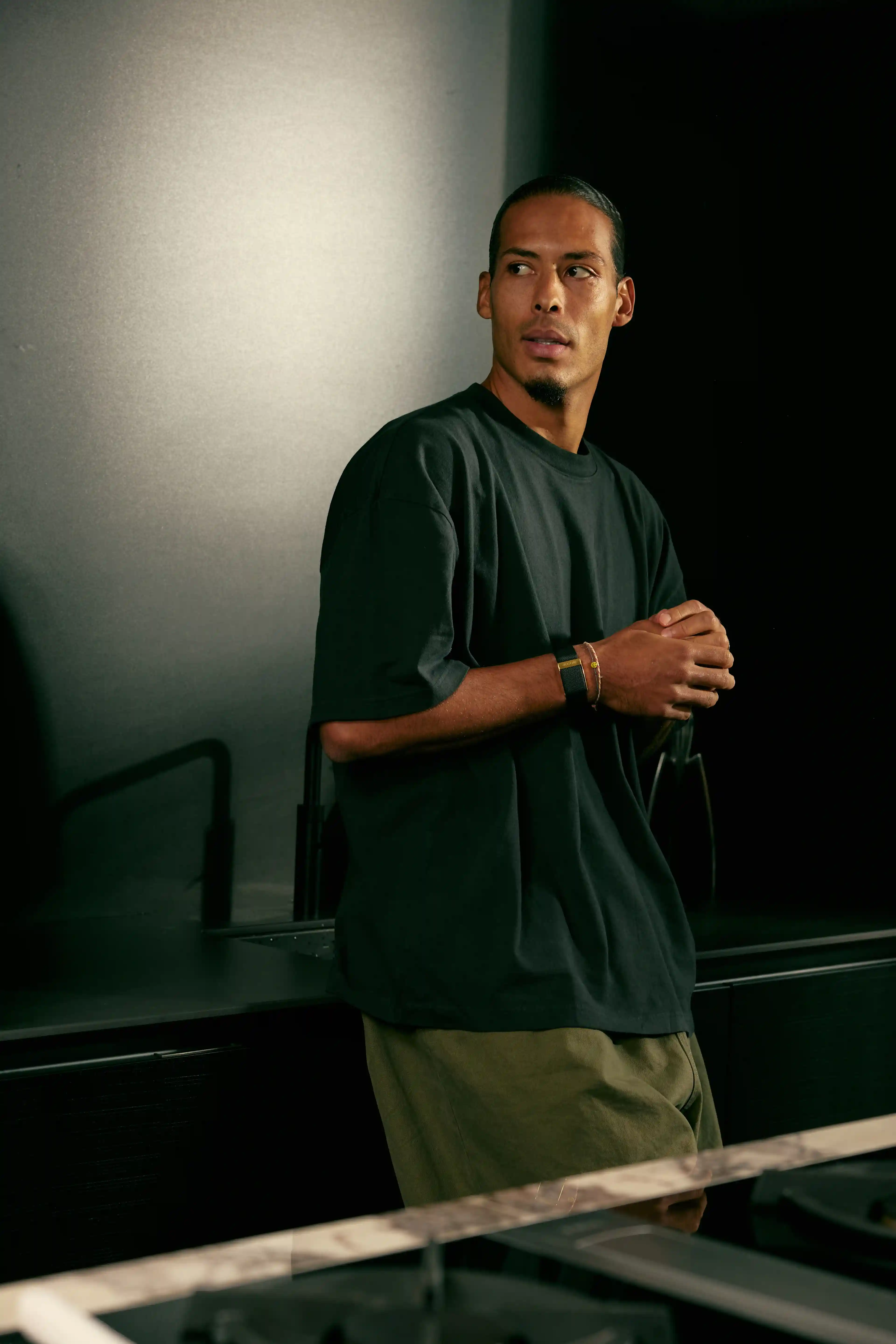 Virgil Van Dijk wearing a WHOOP 5.0 band in a modern kitchen, casual pose, highlighting everyday wear for continuous health and recovery tracking.